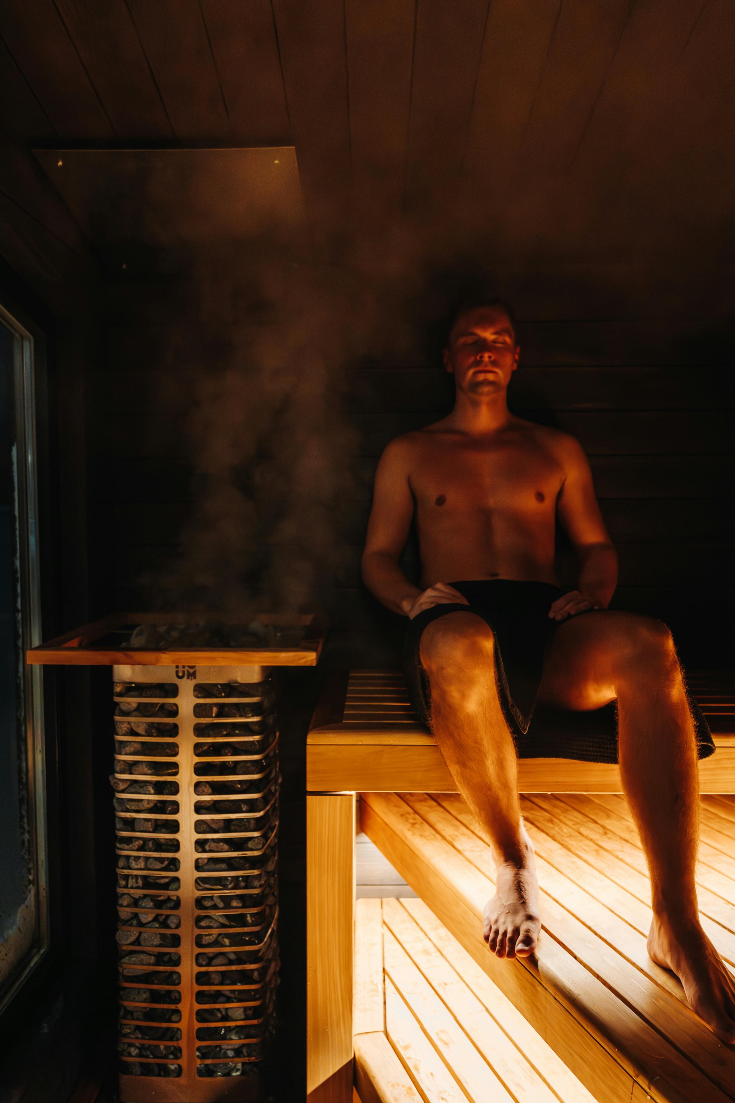 Muž sedí v sauně u horkého saunového kamna