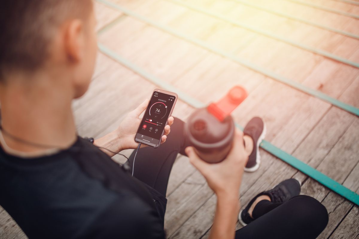 sportovec držící láhev s vodou a telefon