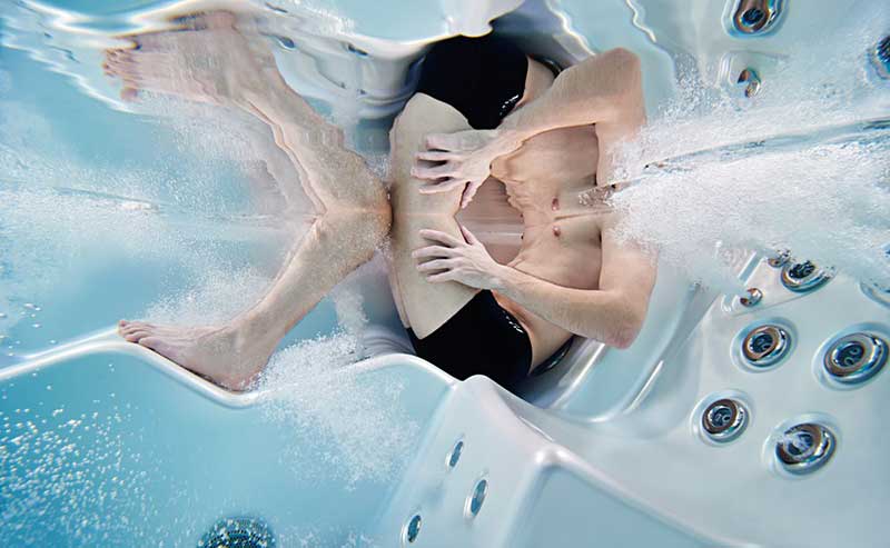 Žena relaxující v ergonomickém lehátku vířivkového bazénu USSPA s hydromasážními tryskami v provozu