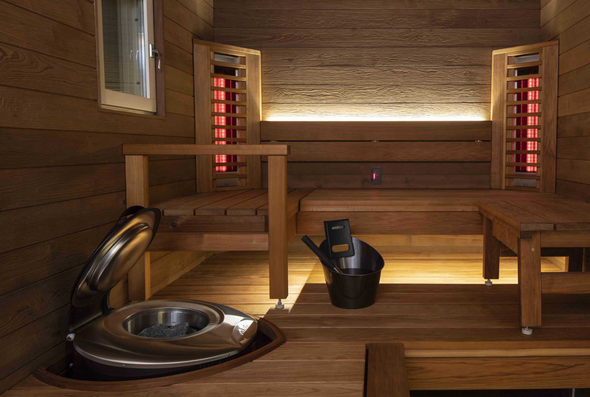 Interiér infrasauny s dřevěnými lavicemi, topnými tělesy a kamny pro relaxaci a wellness